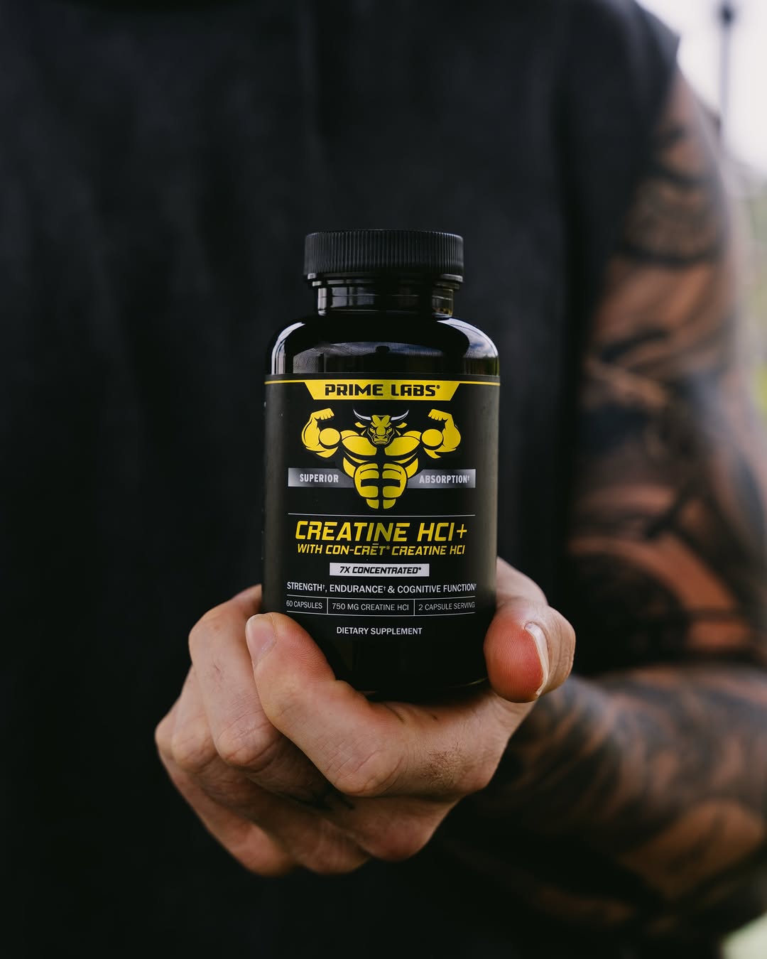 Tattooed hand holding a Prime Labs Creatine HCl+ bottle with CON-CRET creatine HCl label — is a creatine loading phase necessary